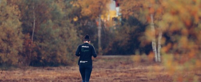 Runner jogging along a wooden boardwalk trail surrounded by bright autumn foliage