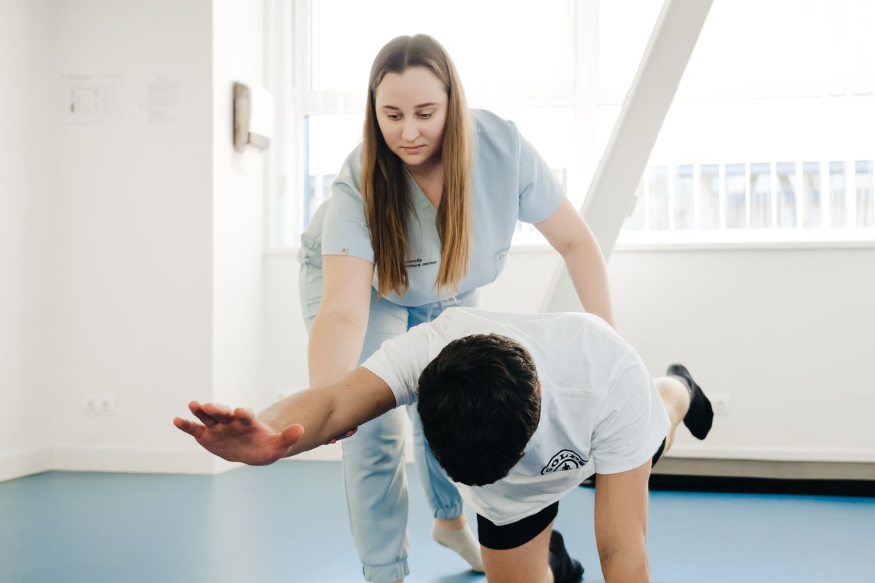 Physical therapist guiding a patient through a bird-dog core stability exercise in a bright clinic
